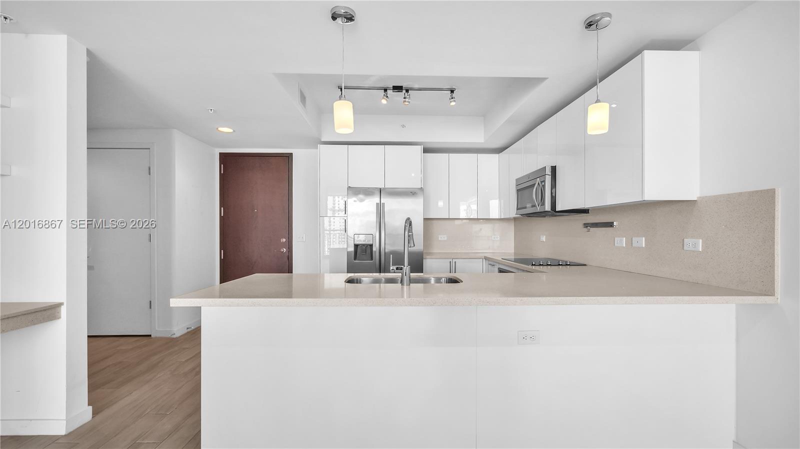 A modern kitchen features white cabinetry, stainless steel appliances, and a central island with seating — 999 SW 1st Ave # 2009, Miami FL 33130, MIAMI, FL