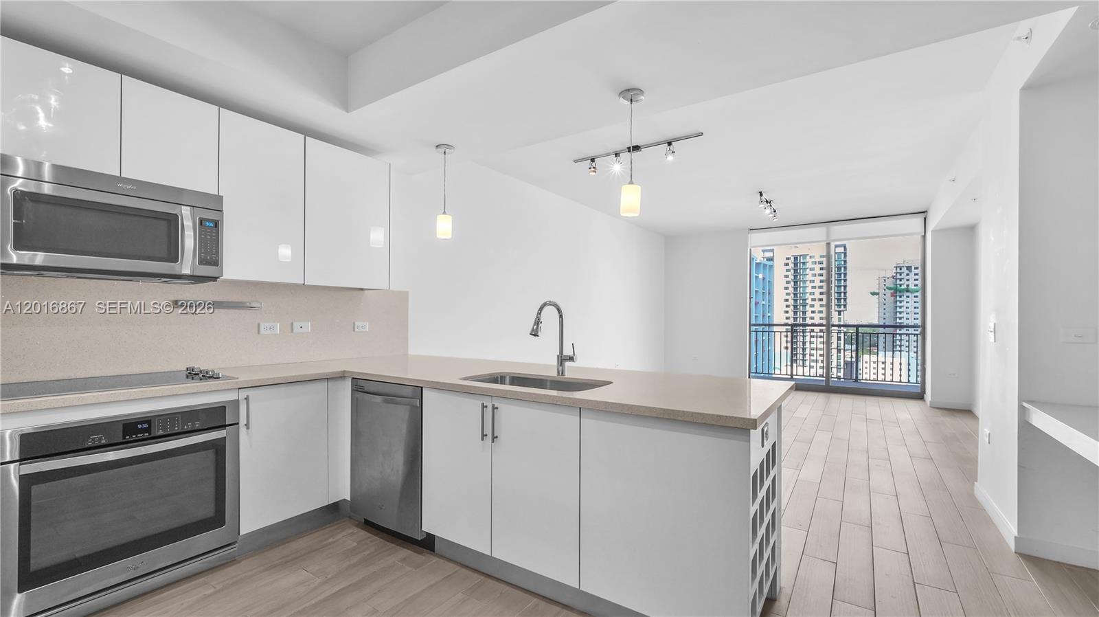 A modern kitchen with white cabinets, stainless steel appliances, and a view of city buildings — 999 SW 1st Ave # 2009, Miami FL 33130, MIAMI, FL