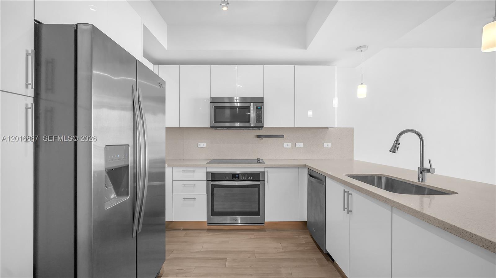 A modern kitchen features white cabinets, stainless steel appliances, and a light-colored countertop — 999 SW 1st Ave # 2009, Miami FL 33130, MIAMI, FL