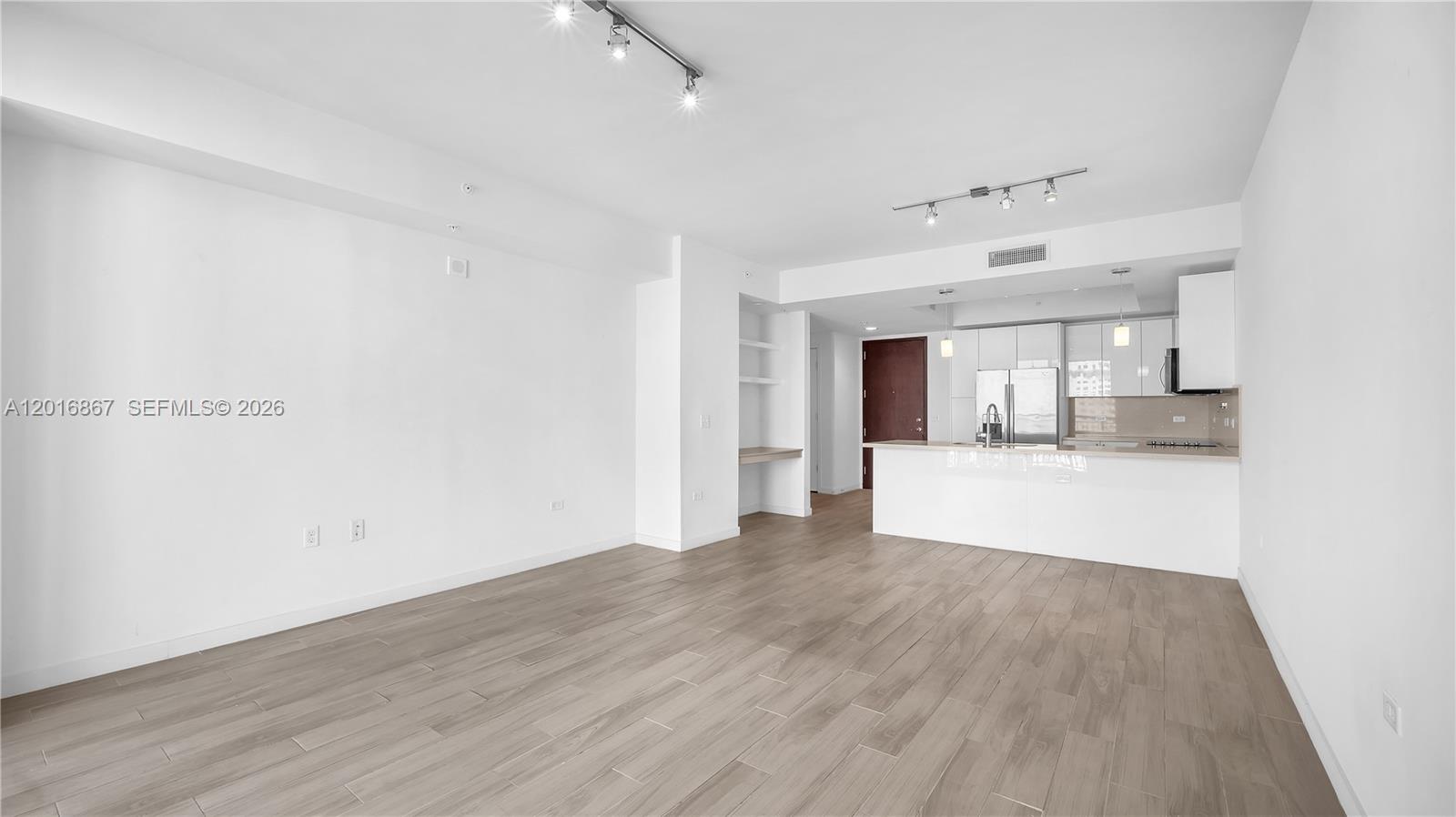 An open-concept living area features light wood-look flooring, white walls, and a modern kitchen — 999 SW 1st Ave # 2009, Miami FL 33130, MIAMI, FL