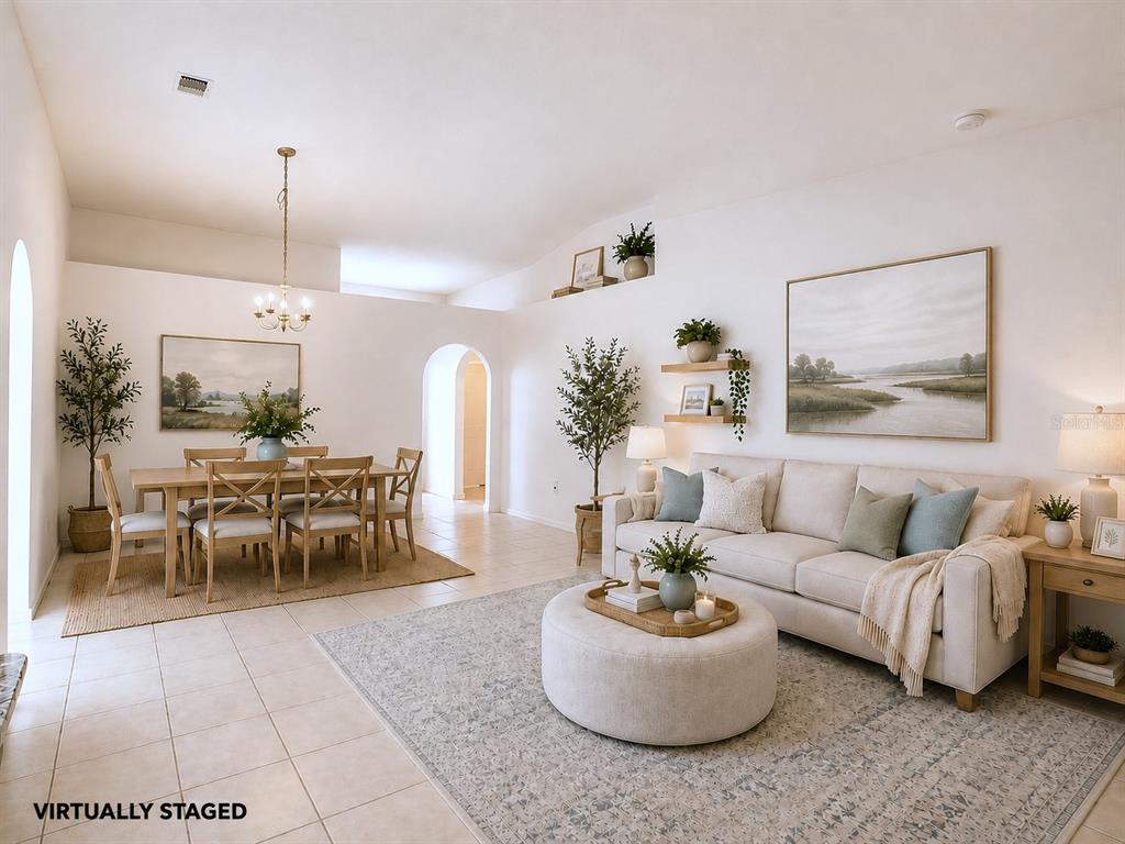 This virtually staged living and dining room features tile floors, white walls, and vaulted ceilings — 10155 LAXTON STREET, ORLANDO, FL
