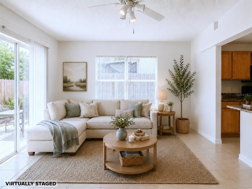 A living room with a sectional sofa, round coffee table, and a ceiling fan — 10155 LAXTON STREET, ORLANDO, FL