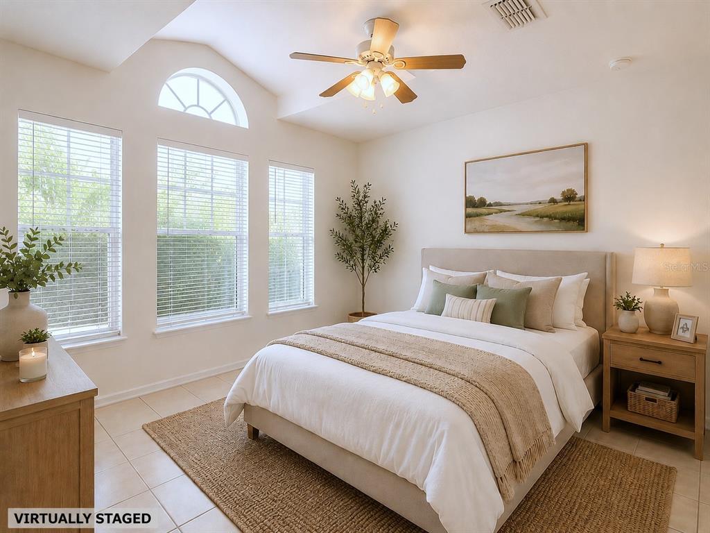 A bedroom with a vaulted ceiling, ceiling fan, three windows, and a queen-sized bed — 10155 LAXTON STREET, ORLANDO, FL