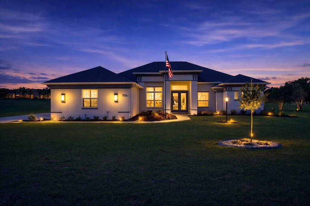 A single-story house with a flag pole and landscape lighting at dusk — 418 N CHERRY POP DRIVE, INVERNESS, FL