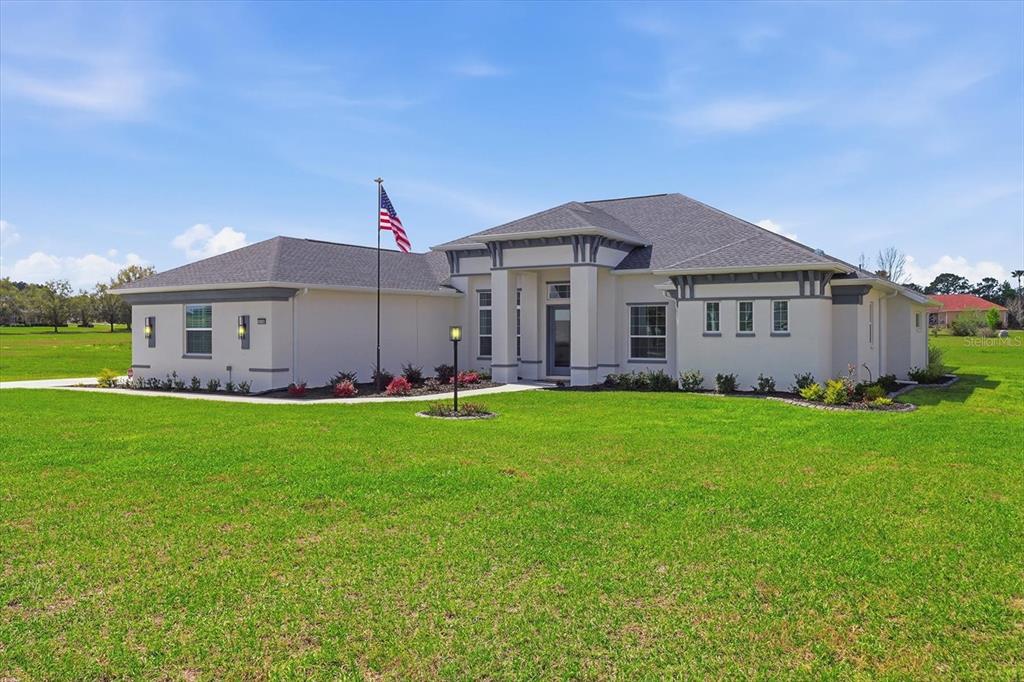 A single-story house with a light-colored exterior, gray roof, and an American flag in front — 418 N CHERRY POP DRIVE, INVERNESS, FL