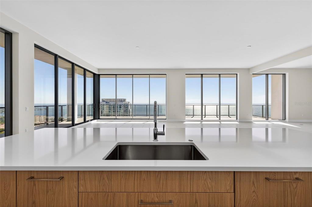 A modern kitchen island with a stainless steel sink overlooks a room with floor-to-ceiling windows — 275 1ST AVENUE S UNIT 4202, ST PETERSBURG, FL