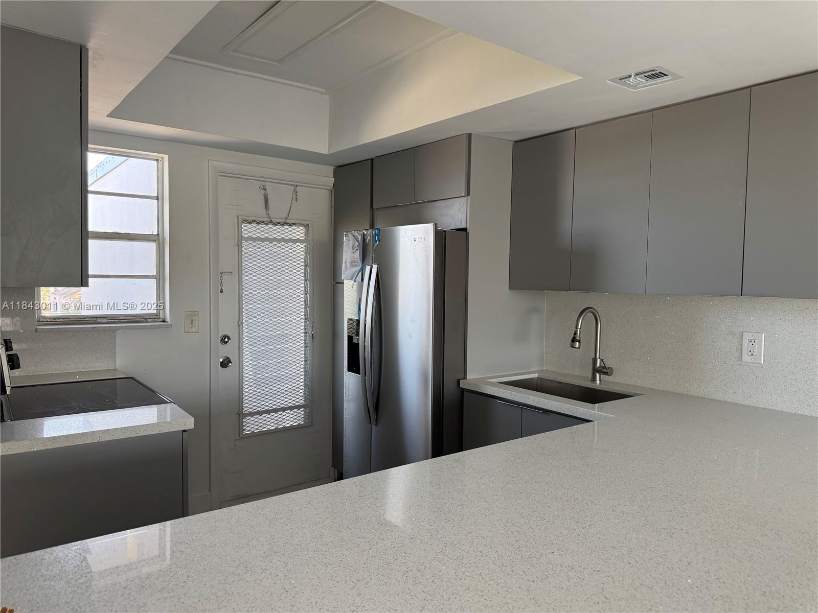 A kitchen features gray flat-panel cabinets, stainless steel appliances, and white speckled quartz countertops — 1333 E Hallandale Beach Blvd # 444, Hallandale Beach FL 33009, HALLANDALE BEACH, FL