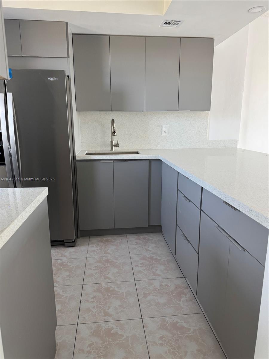 A kitchen features gray flat-panel cabinets, white speckled countertops, and light-colored tiled flooring — 1333 E Hallandale Beach Blvd # 444, Hallandale Beach FL 33009, HALLANDALE BEACH, FL