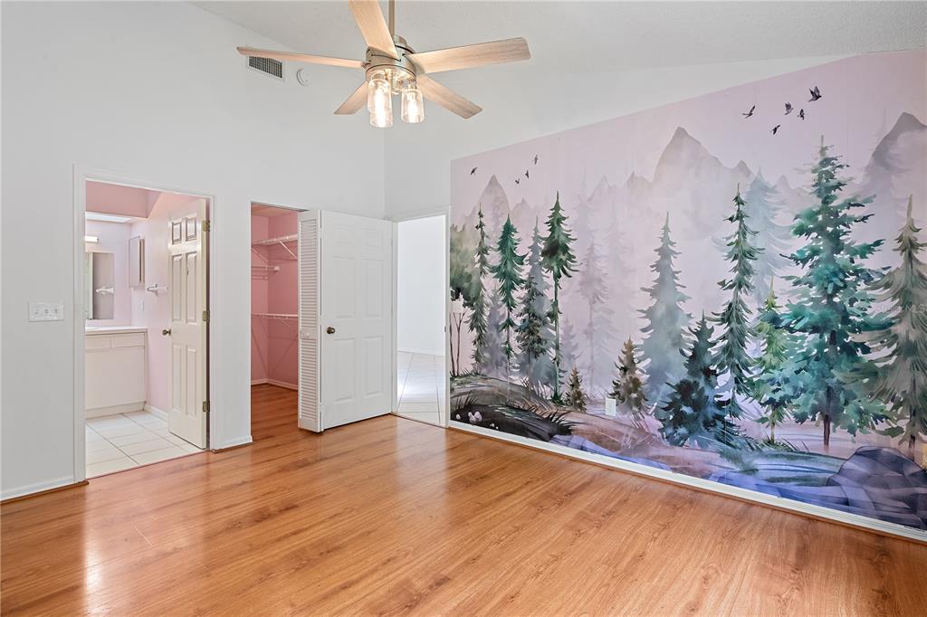 A bedroom with wood flooring, a ceiling fan, and a large mountain forest wall mural — 5647 MONTE ROSSO ROAD, SARASOTA, FL