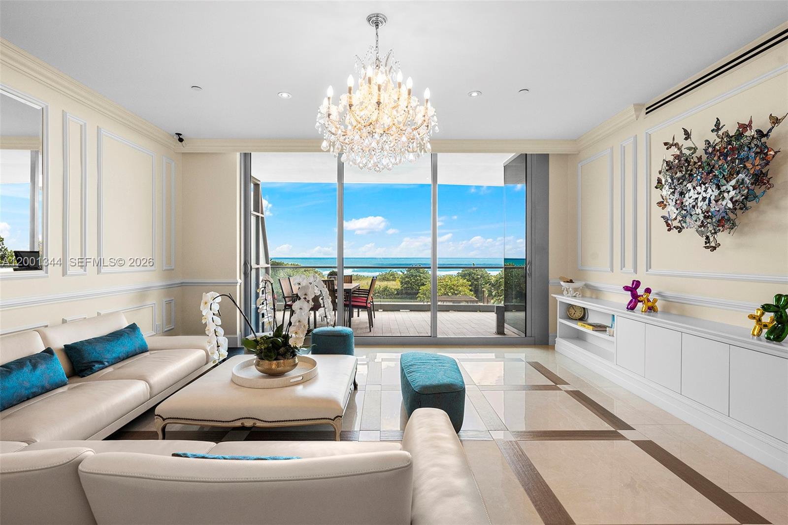 A living room with a crystal chandelier, white leather sofas, and a balcony overlooking the ocean — 9349 Collins Ave # 203, Surfside FL 33154, SURFSIDE, FL