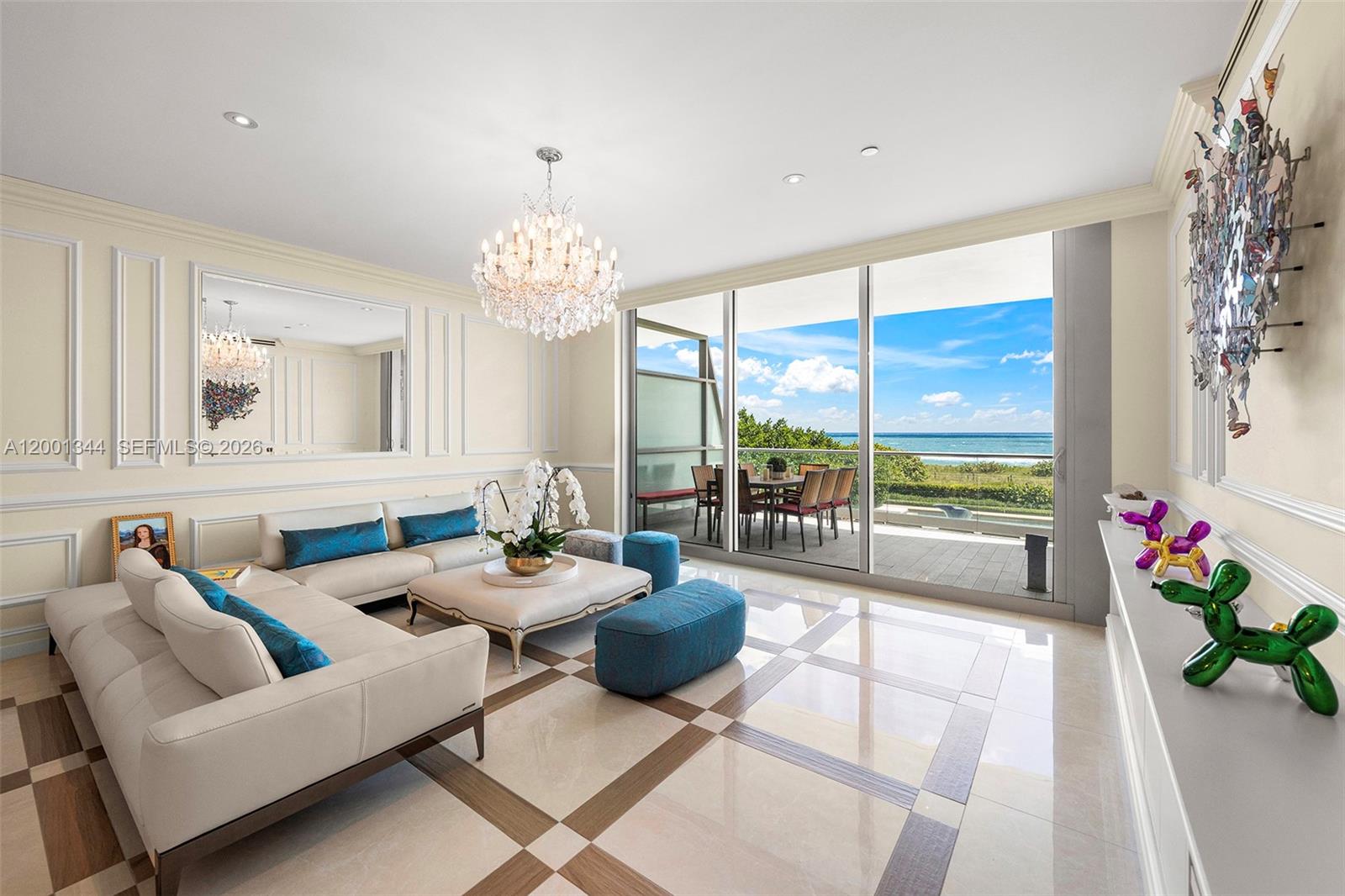 A living room with white sofas, a crystal chandelier, and a balcony overlooking the ocean — 9349 Collins Ave # 203, Surfside FL 33154, SURFSIDE, FL