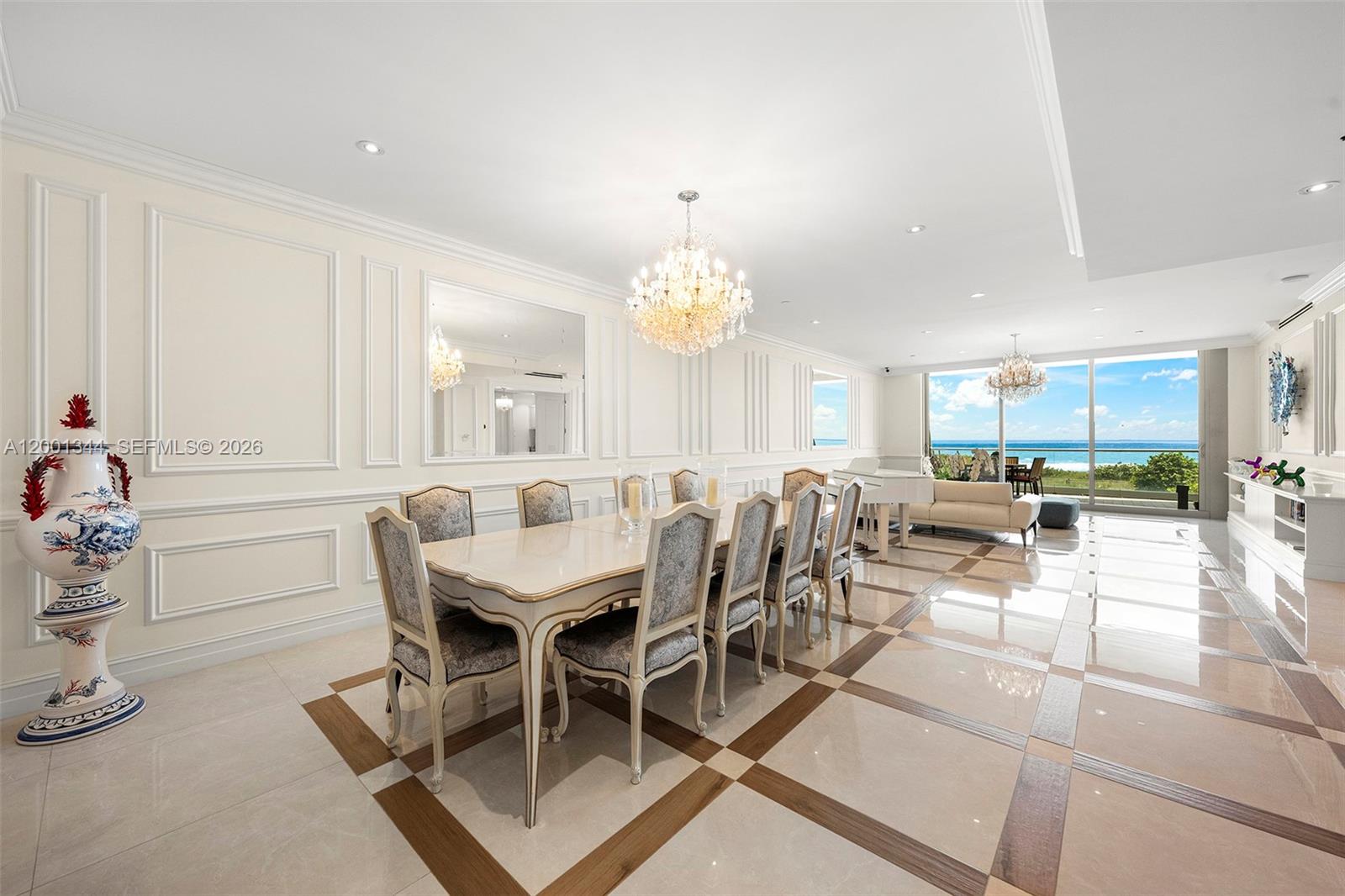 A formal dining room features a long table, crystal chandeliers, and floor-to-ceiling ocean views — 9349 Collins Ave # 203, Surfside FL 33154, SURFSIDE, FL