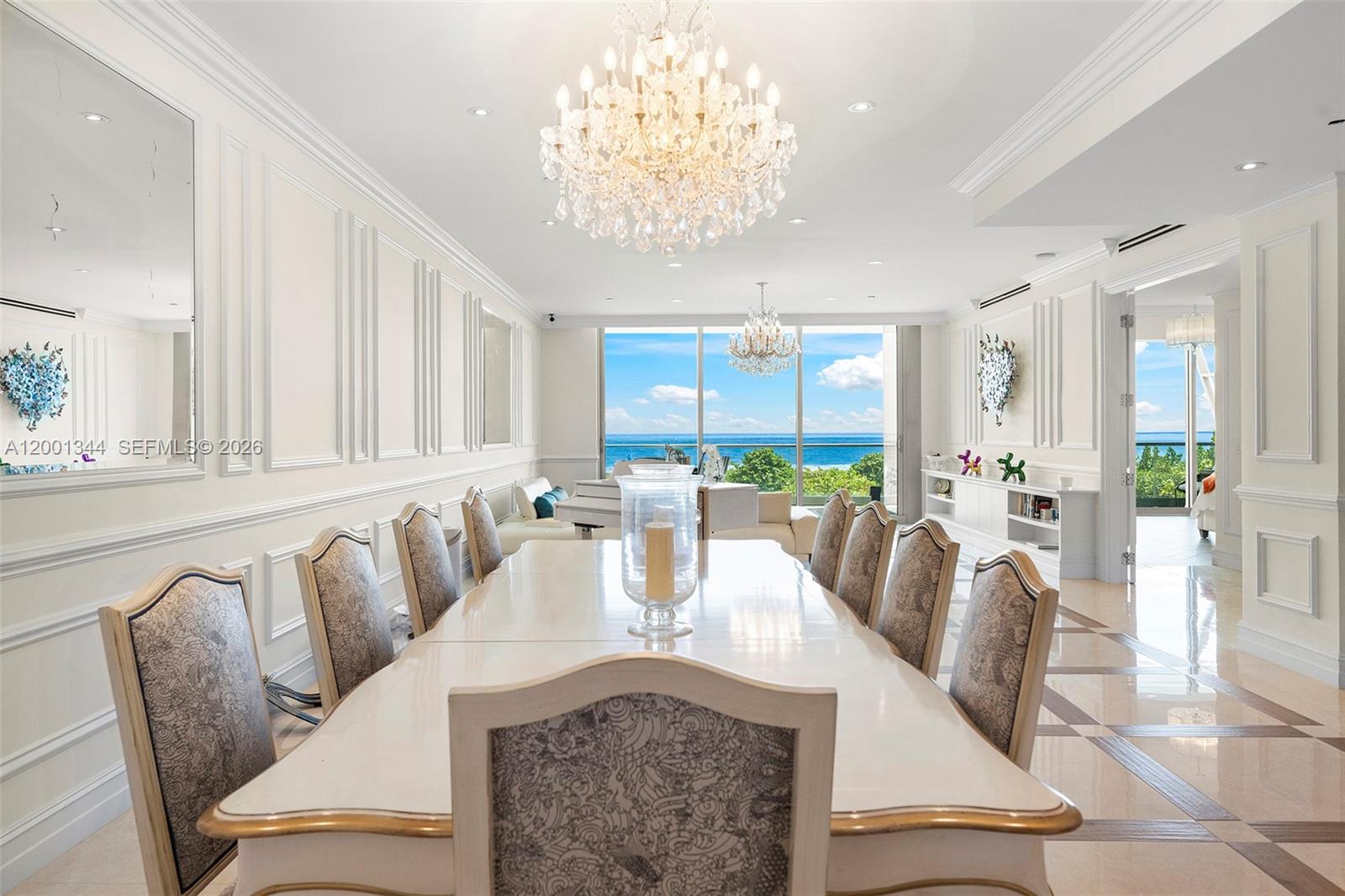 A formal dining room features a long white table, crystal chandeliers, and ocean views — 9349 Collins Ave # 203, Surfside FL 33154, SURFSIDE, FL