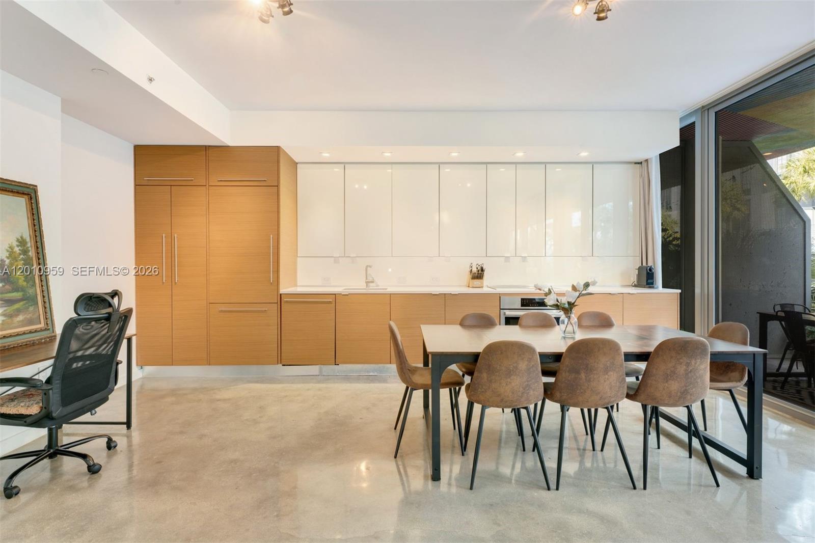 A modern kitchen features wood and white cabinetry, a dining table, and polished concrete floors — 250 NW 24th St # 2B, Miami FL 33127, MIAMI, FL