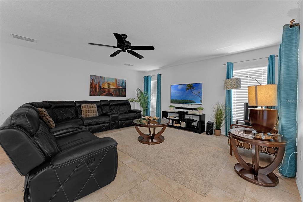 A living room features a large black sectional sofa, a coffee table, and a television — 2631 SANTOSH COVE, KISSIMMEE, FL
