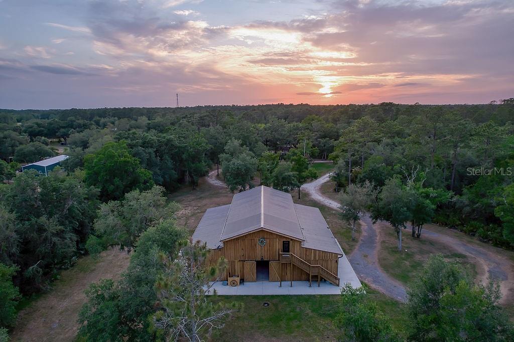 An aerial view of a wooden barn with a metal roof at sunset — 963 LAKE ASHBY ROAD, NEW SMYRNA BEACH, FL