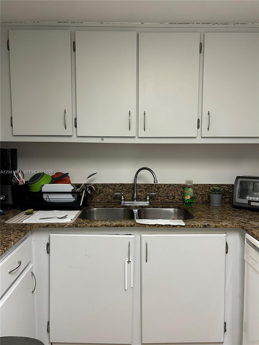 A kitchen features white cabinets, a double-basin stainless steel sink, and speckled granite countertops — 1975 Normandy Dr # 301, Miami Beach FL 33141, MIAMI BEACH, FL