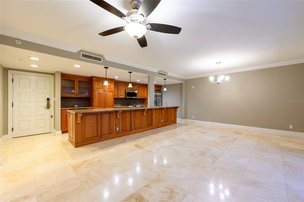 A kitchen with wooden cabinets and a large island opens into a spacious dining area — 36750 US HIGHWAY 19 N UNIT 04221, PALM HARBOR, FL