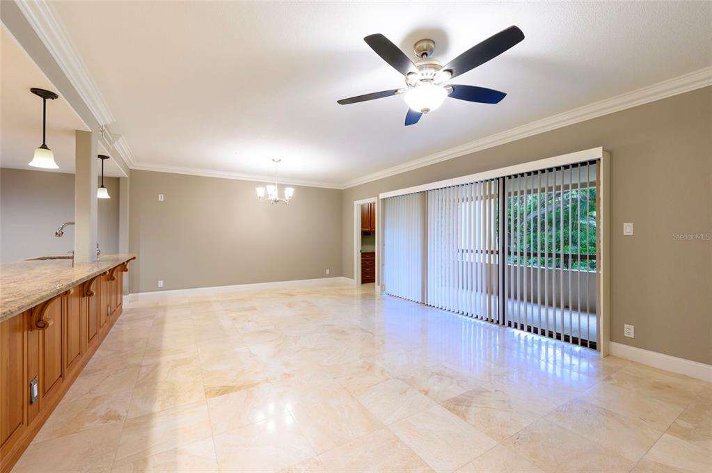 A spacious room features light tile flooring, a ceiling fan, and sliding glass patio doors — 36750 US HIGHWAY 19 N UNIT 04221, PALM HARBOR, FL