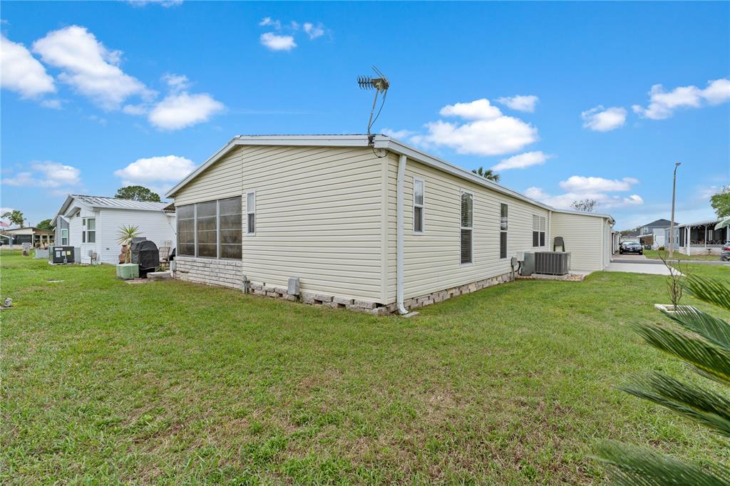 The exterior of a light-colored manufactured home features vinyl siding, a metal roof, and windows — 3120 POND HOLLOW STREET, WESLEY CHAPEL, FL