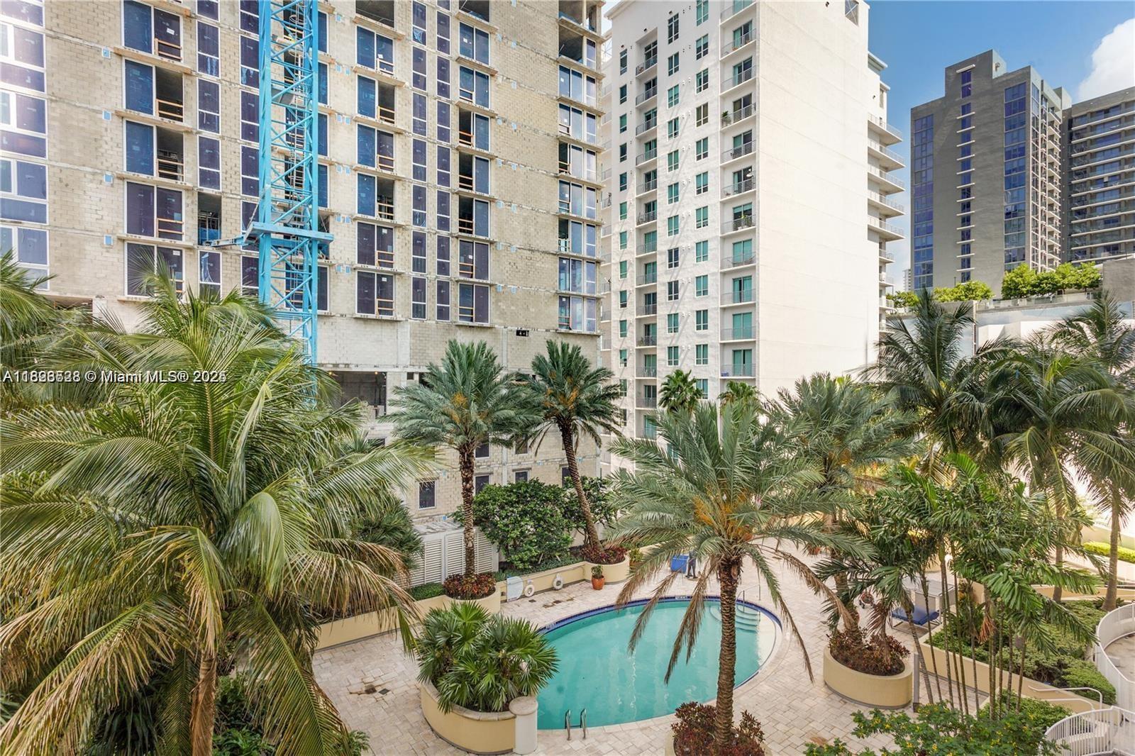 An outdoor swimming pool surrounded by palm trees and high-rise apartment buildings — 253 NE 2nd St # 1108, Miami FL 33132, MIAMI, FL