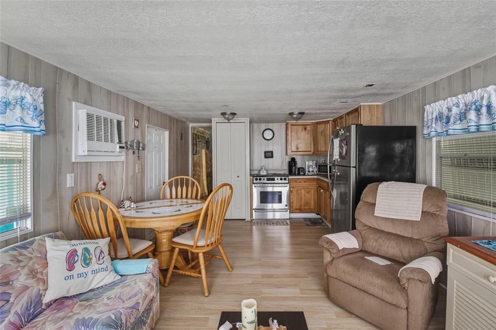 A combined kitchen and living area features wood-paneled walls, light flooring, and a dining set — 12766 SEMINOLE BOULEVARD UNIT 3, LARGO, FL