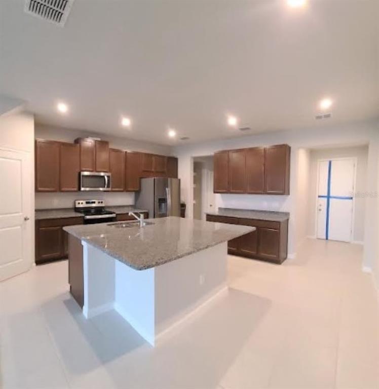 A kitchen with dark wood cabinets, granite countertops, a central island, and stainless steel appliances — 2525 ARBOR WIND DRIVE, LUTZ, FL