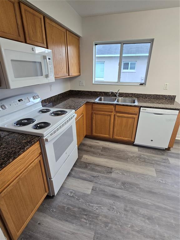 A kitchen features oak cabinets, granite countertops, white appliances, and gray wood-look flooring — 11010 WHITECAP DRIVE, RIVERVIEW, FL