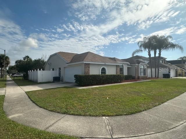 A single-story house with a tan exterior, a shingled roof, and a white privacy fence — 12686 NEWFIELD DRIVE, ORLANDO, FL