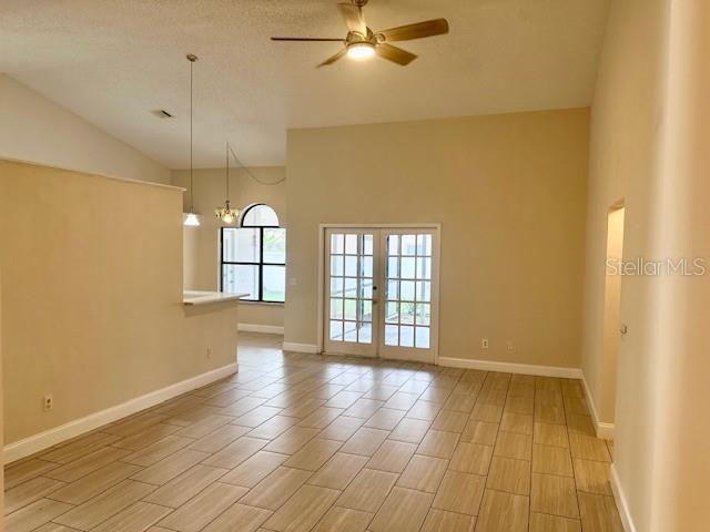 An open living area features vaulted ceilings, tile flooring, and glass doors leading outside — 12686 NEWFIELD DRIVE, ORLANDO, FL