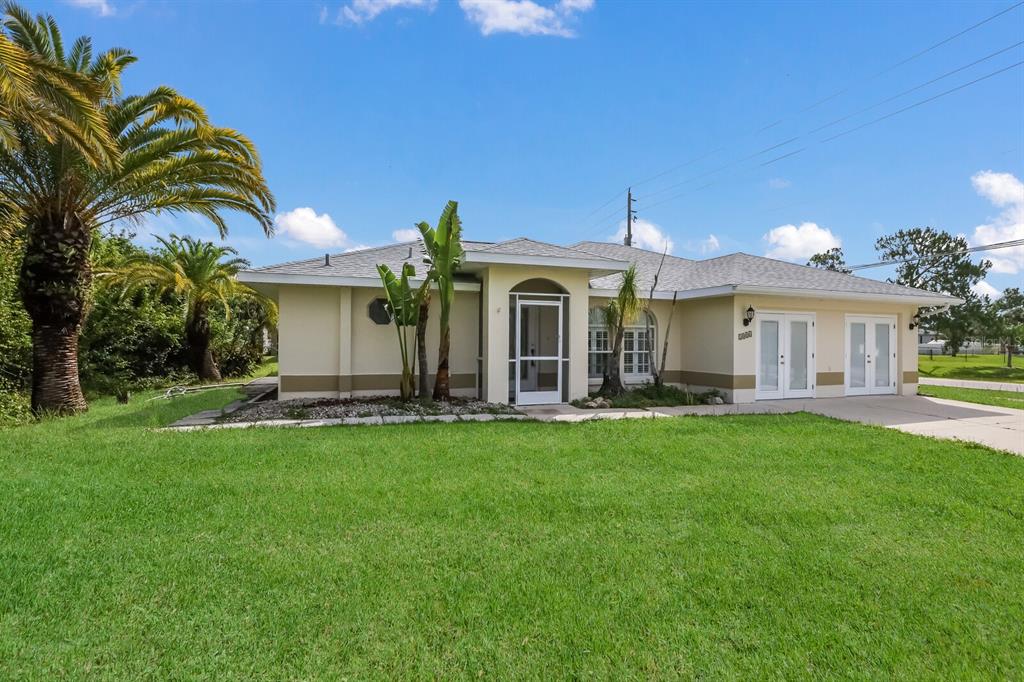 A single-story house with a beige exterior, a screened front door, and a palm tree — 2004 BOCA CHICA AVENUE, NORTH PORT, FL