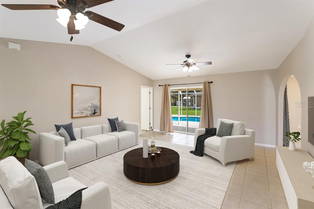 A living room with a vaulted ceiling, white furniture, a dark coffee table, and pool view — 2004 BOCA CHICA AVENUE, NORTH PORT, FL