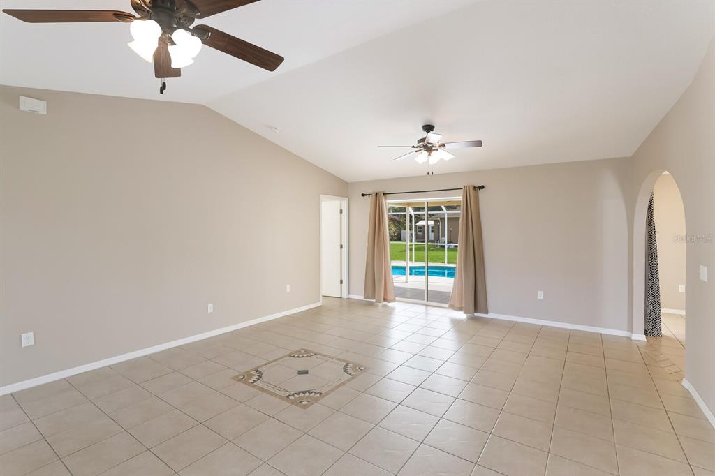 A spacious living room features tile flooring, vaulted ceilings, two ceiling fans, and sliding doors — 2004 BOCA CHICA AVENUE, NORTH PORT, FL