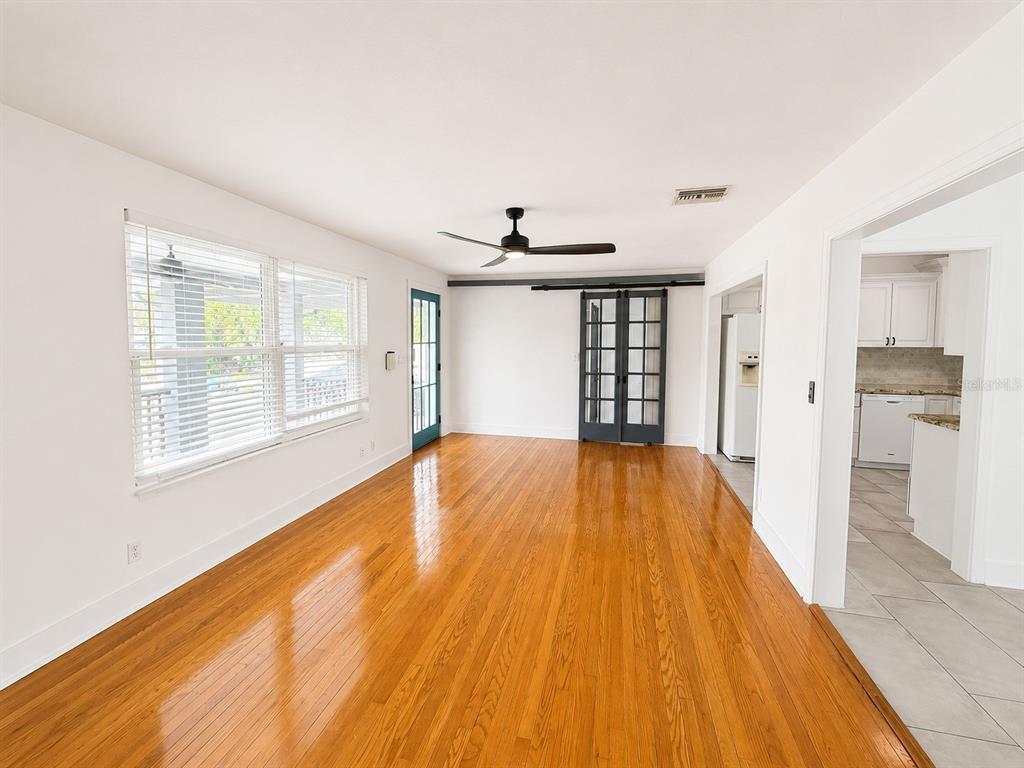 A living room with hardwood floors, a ceiling fan, and sliding glass barn doors — 3815 W NORTH B STREET, TAMPA, FL
