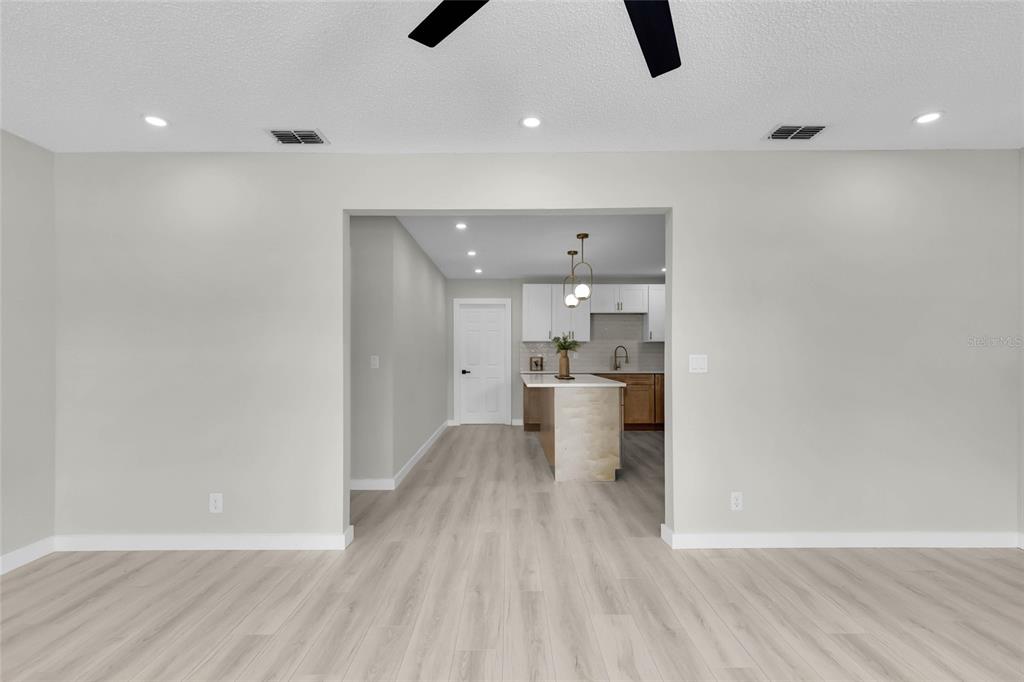 A view from a living area looking through an opening into a modern kitchen — 9140 SE 155TH PLACE, SUMMERFIELD, FL