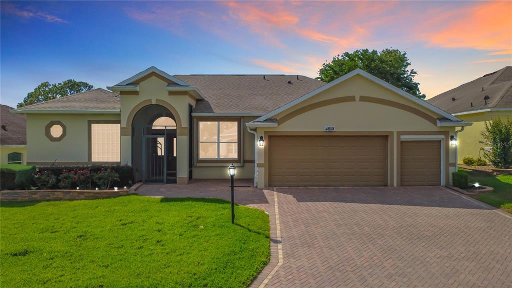 A single-story house with a beige exterior, a brick driveway, and a three-car garage — 4810 SABLE RIDGE COURT, LEESBURG, FL
