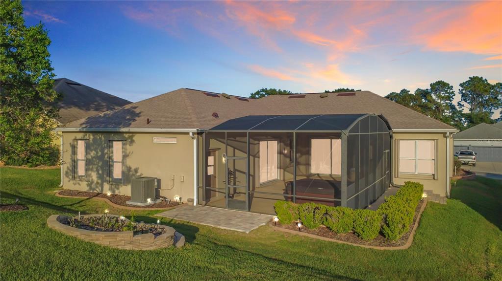 The rear exterior of a house features a screened-in patio, a hot tub, and landscaping — 4810 SABLE RIDGE COURT, LEESBURG, FL