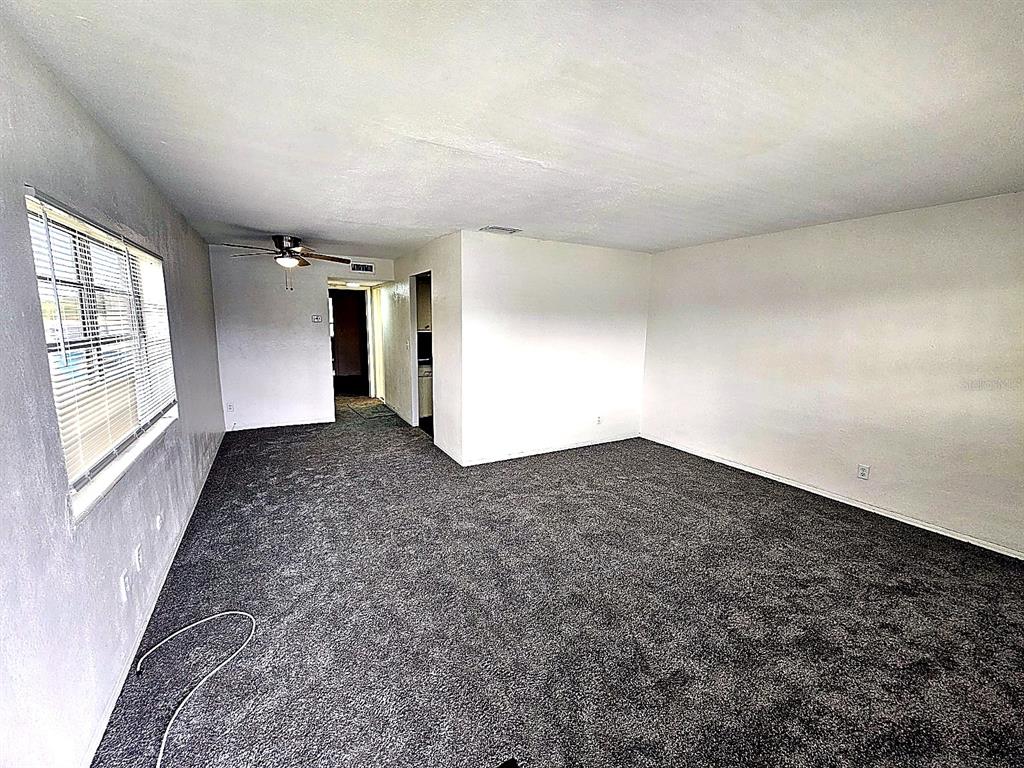 An empty living room features gray carpet, white walls, and a ceiling fan — 5924 5TH AVENUE N UNIT A7, ST PETERSBURG, FL