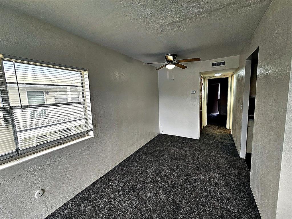 An empty room with dark gray carpet, a ceiling fan, and a window with blinds — 5924 5TH AVENUE N UNIT A7, ST PETERSBURG, FL