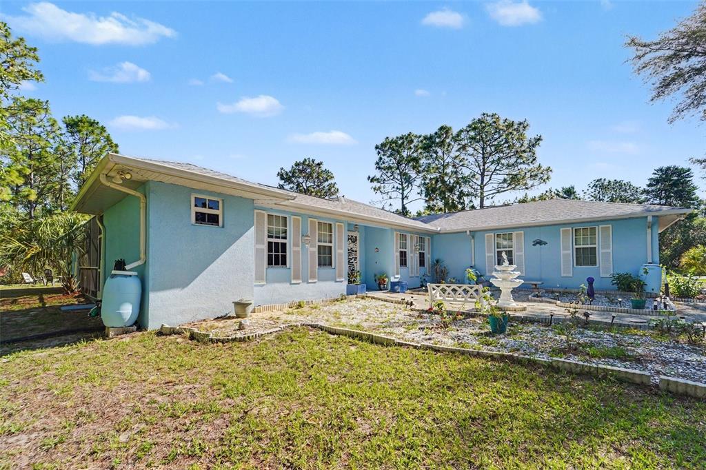 A light blue, single-story ranch house with a gravel driveway and a central fountain — 5432 N PECOS TERRACE, BEVERLY HILLS, FL