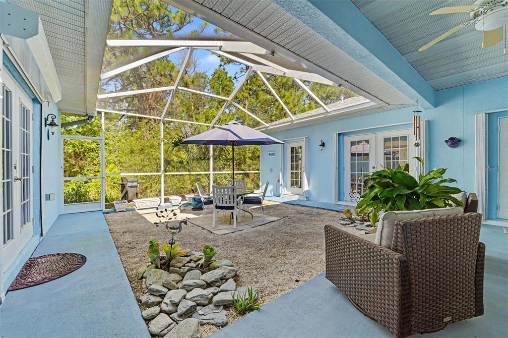A screened-in patio features a gravel floor, a dining set, and blue painted walls — 5432 N PECOS TERRACE, BEVERLY HILLS, FL