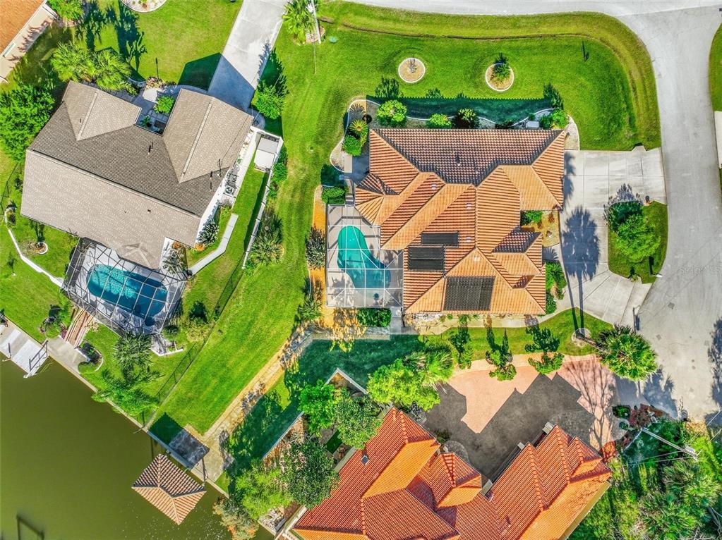 Aerial view of three suburban houses with swimming pools and tiled roofs near a lake — 2 CHER COURT, PALM COAST, FL