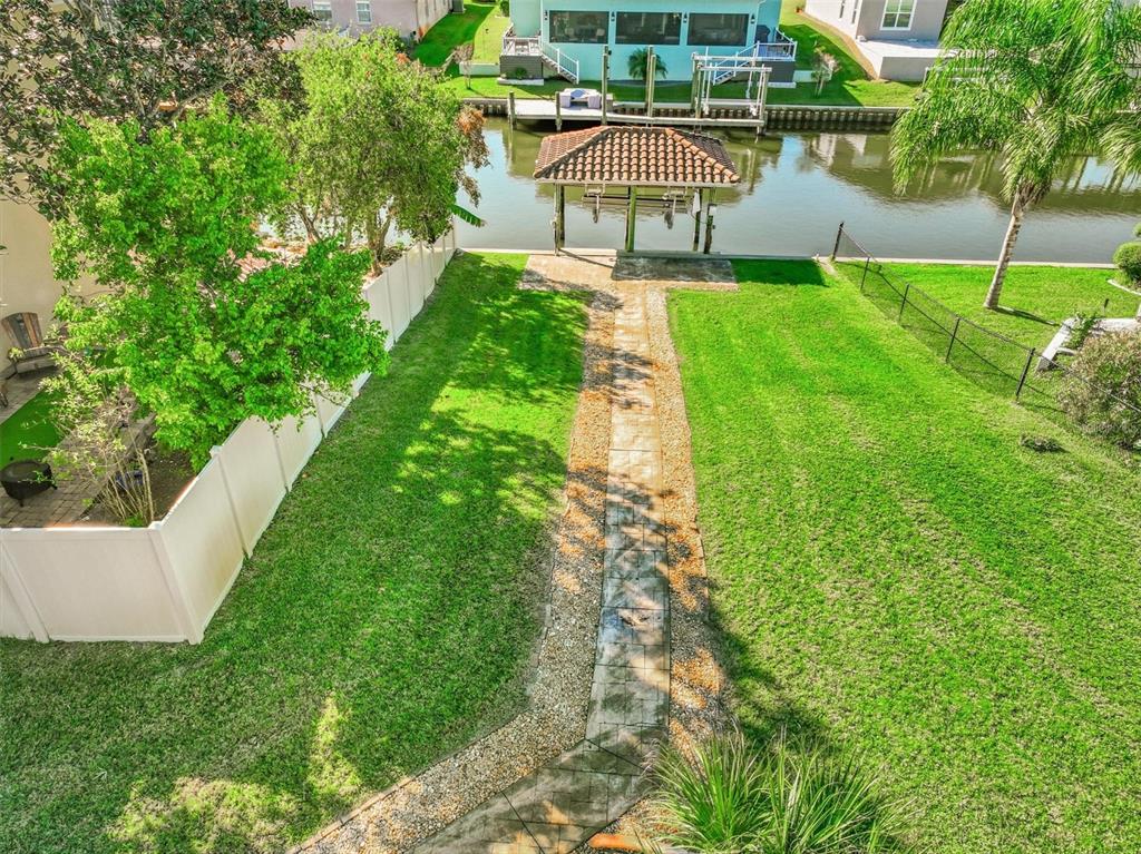 An aerial view of a grassy backyard with a stone walkway leading to a boat dock — 2 CHER COURT, PALM COAST, FL