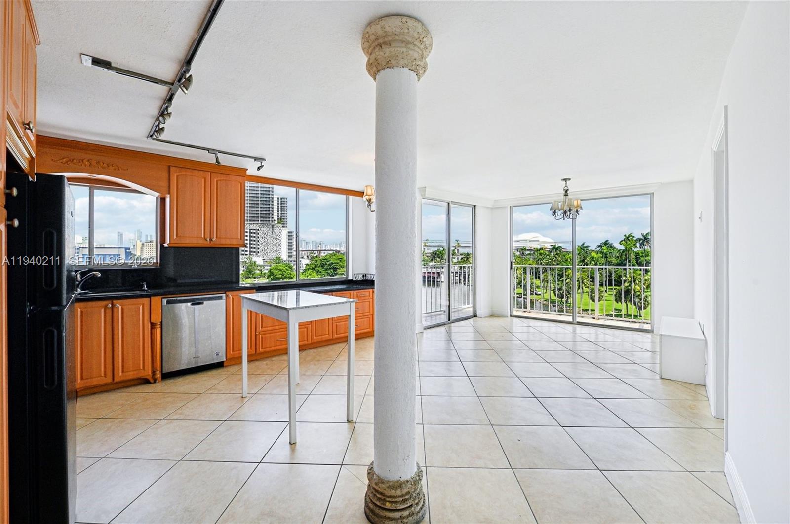 A kitchen and dining area with tile floors, wooden cabinets, and a prominent central column — 1740 NW N River Dr # 614, Miami FL 33125, MIAMI, FL
