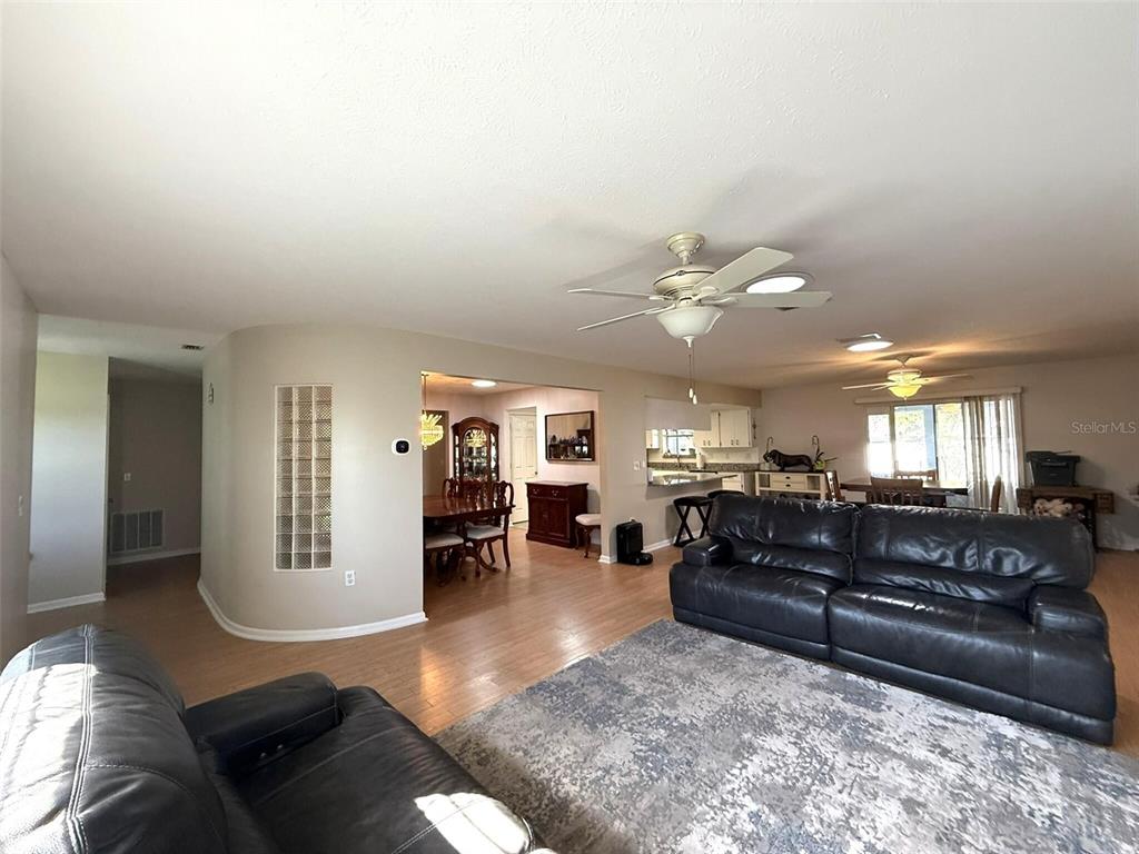 A living room with light wood floors, a gray area rug, and black leather furniture — 3604 E ONYX PLACE, HERNANDO, FL
