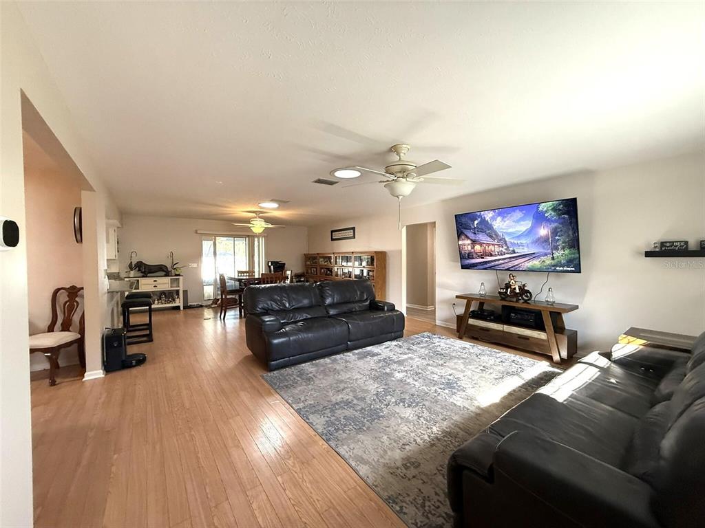 A living room with wood flooring, two black leather sofas, and a wall-mounted television — 3604 E ONYX PLACE, HERNANDO, FL