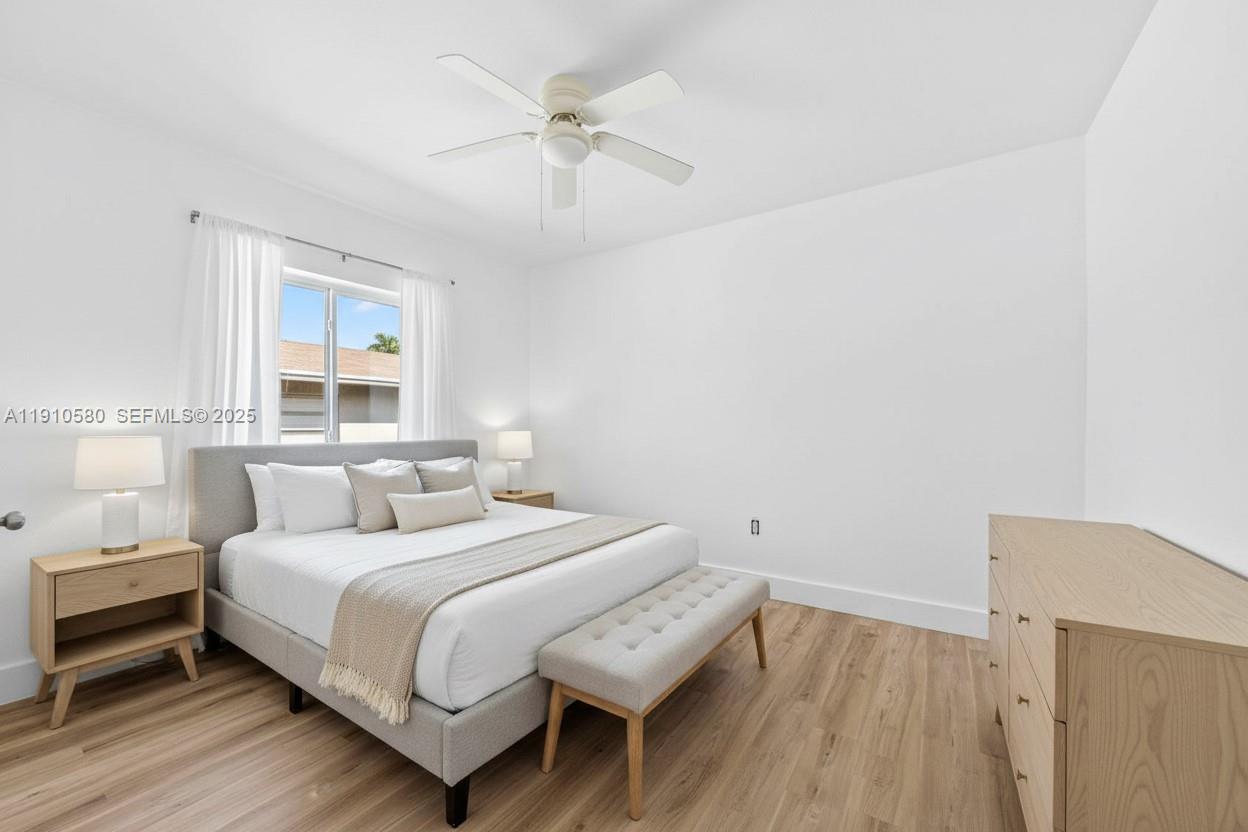 A bedroom features a bed with a gray headboard, light wood flooring, and a ceiling fan — 300 NW 7th Ave # 1, Miami FL 33128, MIAMI, FL
