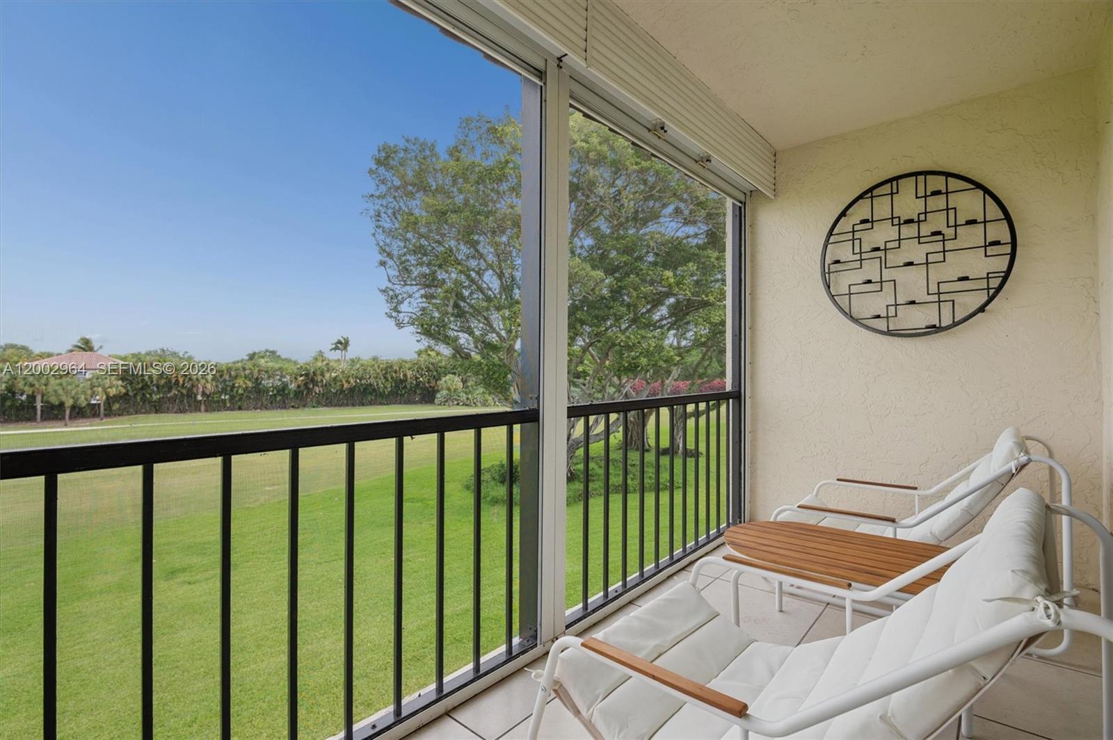A screened-in balcony features white lounge chairs and a view of a grassy field — PEMBROKE PINES, FL
