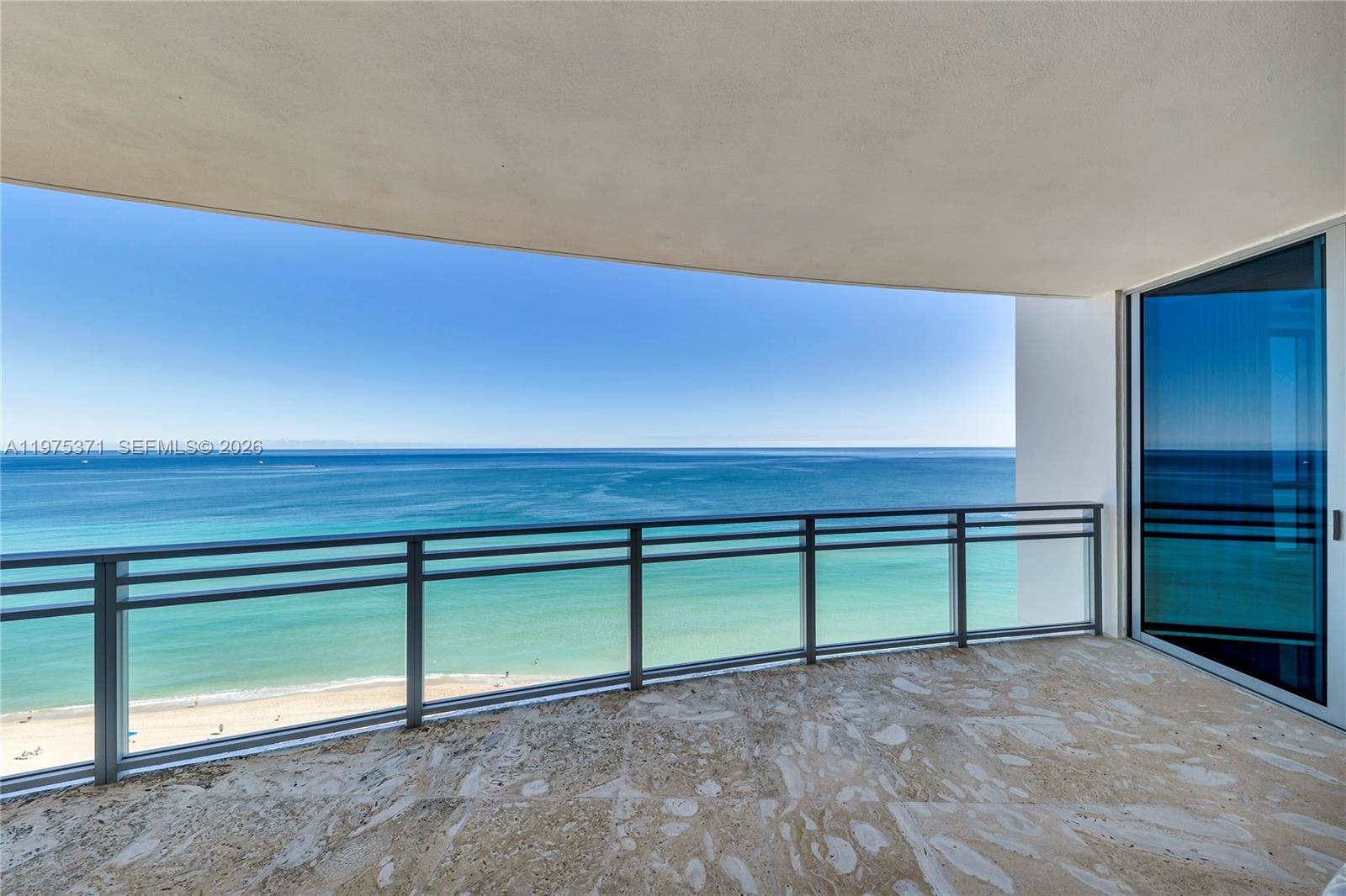 A balcony with stone flooring and a glass railing overlooks the ocean and beach — 3535 S Ocean Dr # 1602, Hollywood FL 33019, HOLLYWOOD, FL