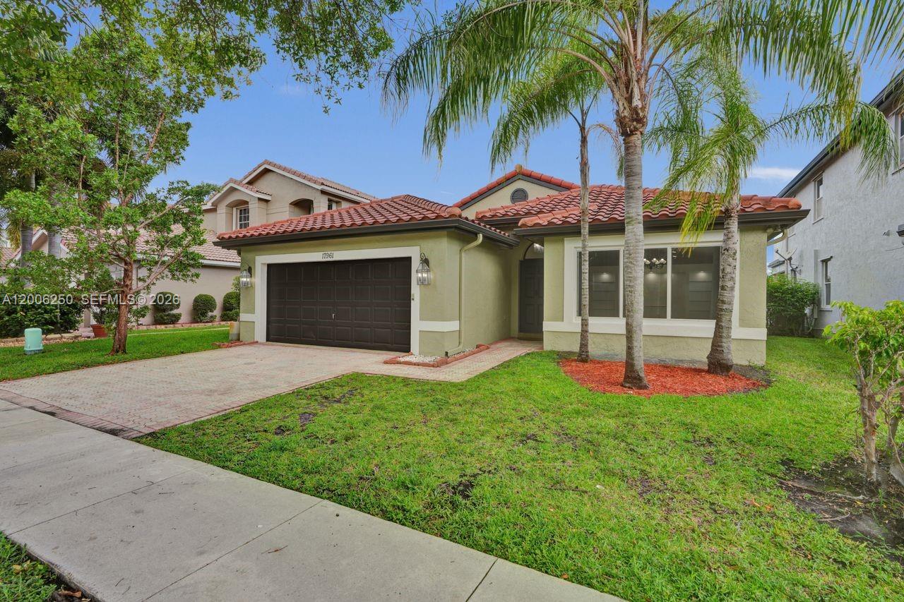 A covered patio with a pergola and tiled floor overlooks a backyard and lake — 17961 SW 27th St, Miramar FL 33029, MIRAMAR, FL
